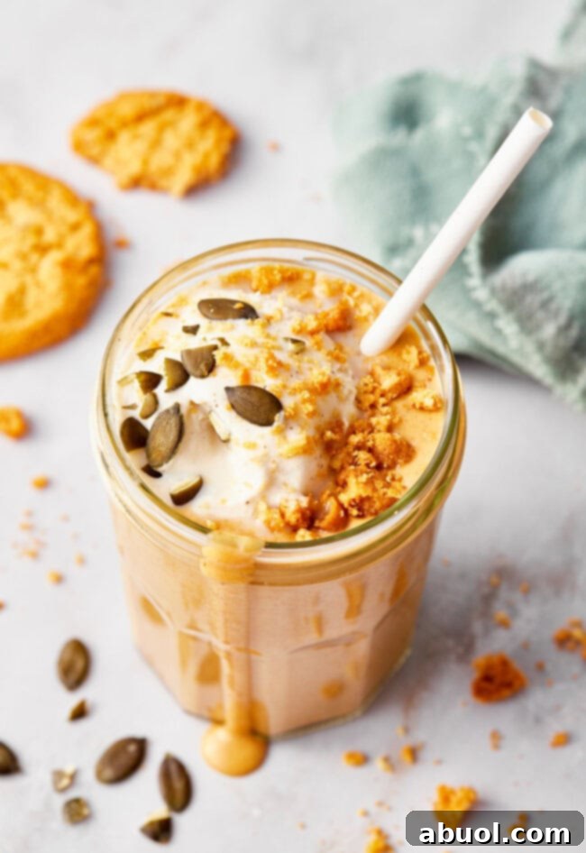 A creamy, rich pumpkin shake served in a clear glass with a cheerful striped straw, inviting you to take a sip and enjoy the essence of fall.