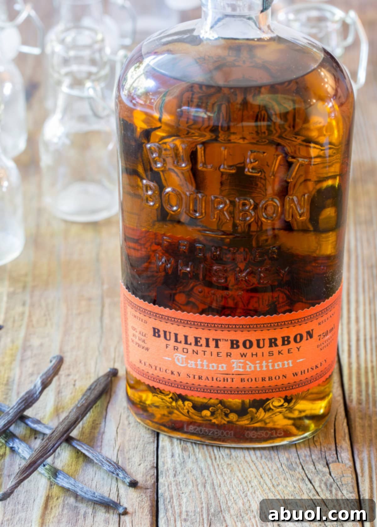 Bottle of bourbon with vanilla pods next to it. 