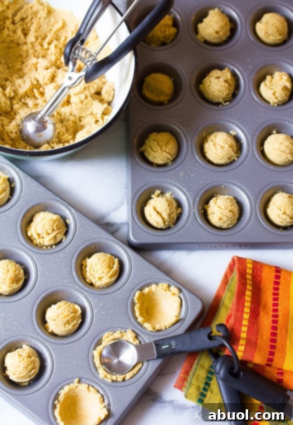 Masa batter being carefully spooned into mini muffin baking containers.