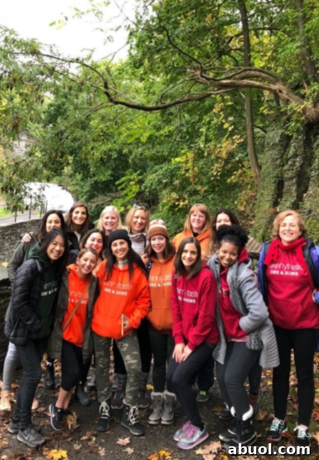 A group of fourteen women, all wearing matching SkinnyTaste hoodies, smiling and posing together during their glamping adventure.