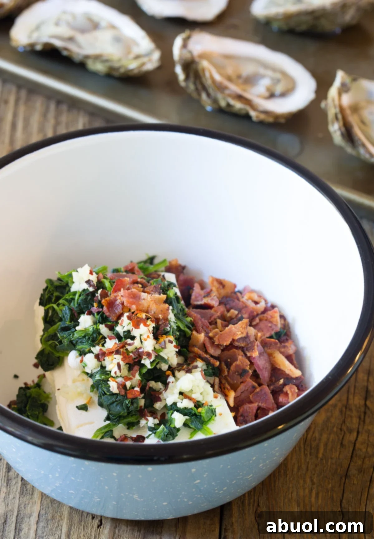 Close-up of the rich, cheesy filling bubbling over cooked oysters, mixed with bacon and spinach, fresh from the oven.