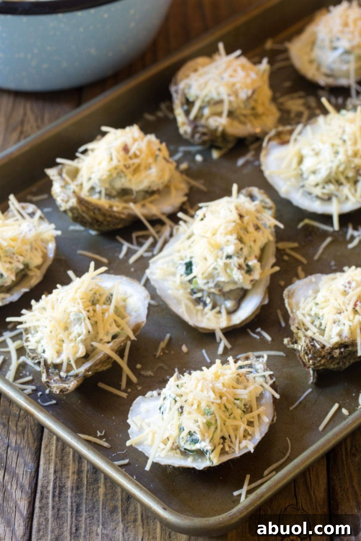 A baking tray showcasing baked oysters with a generous topping of melted three-cheese and bacon, ready to be served.
