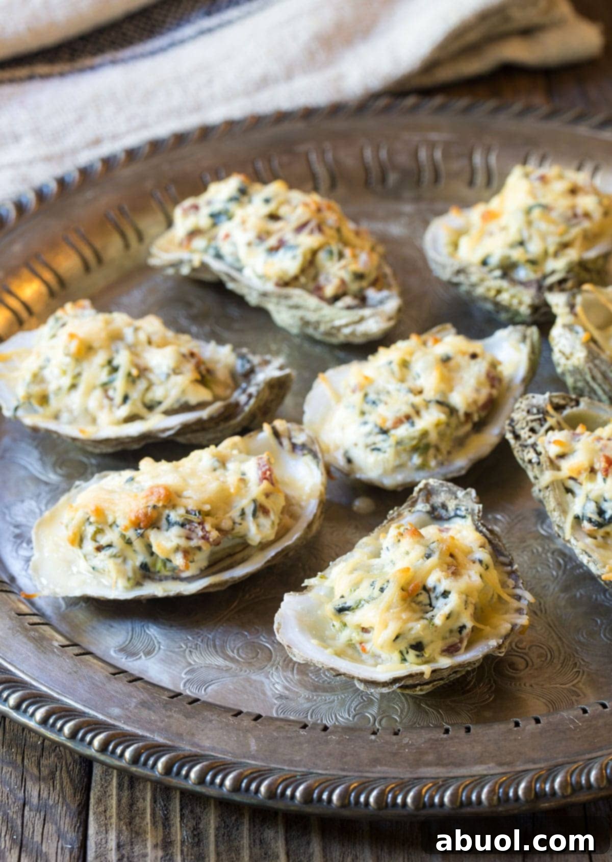 The best baked oysters recipe, presented on a serving tray, showing off the perfectly melted, golden-brown cheese topping.