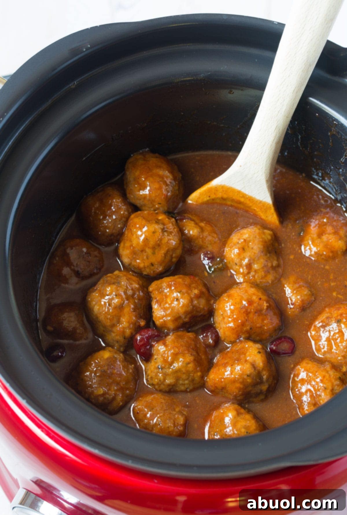 Top view of this crock pot barbecue meatballs with a wooden spoon to stir