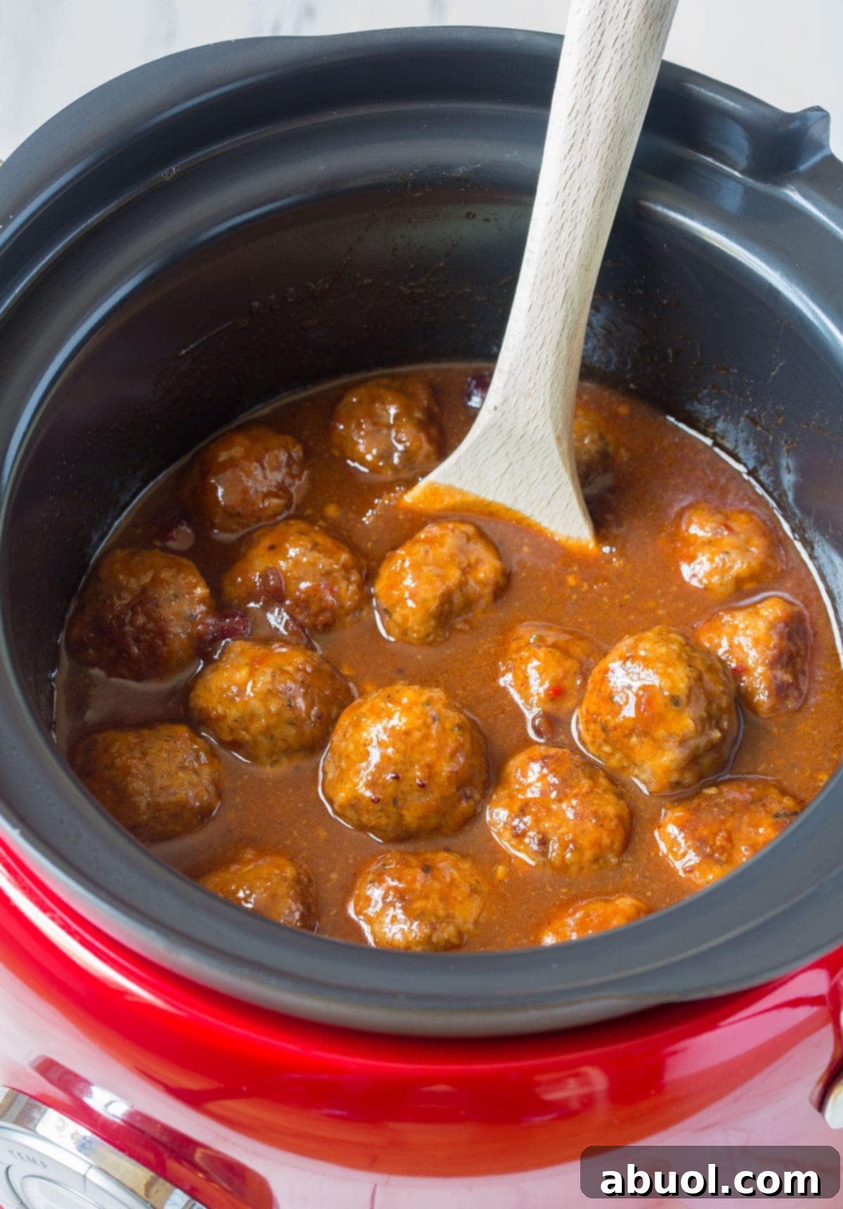 slow cooker cocktail meatballs in sauce with wooden spoon