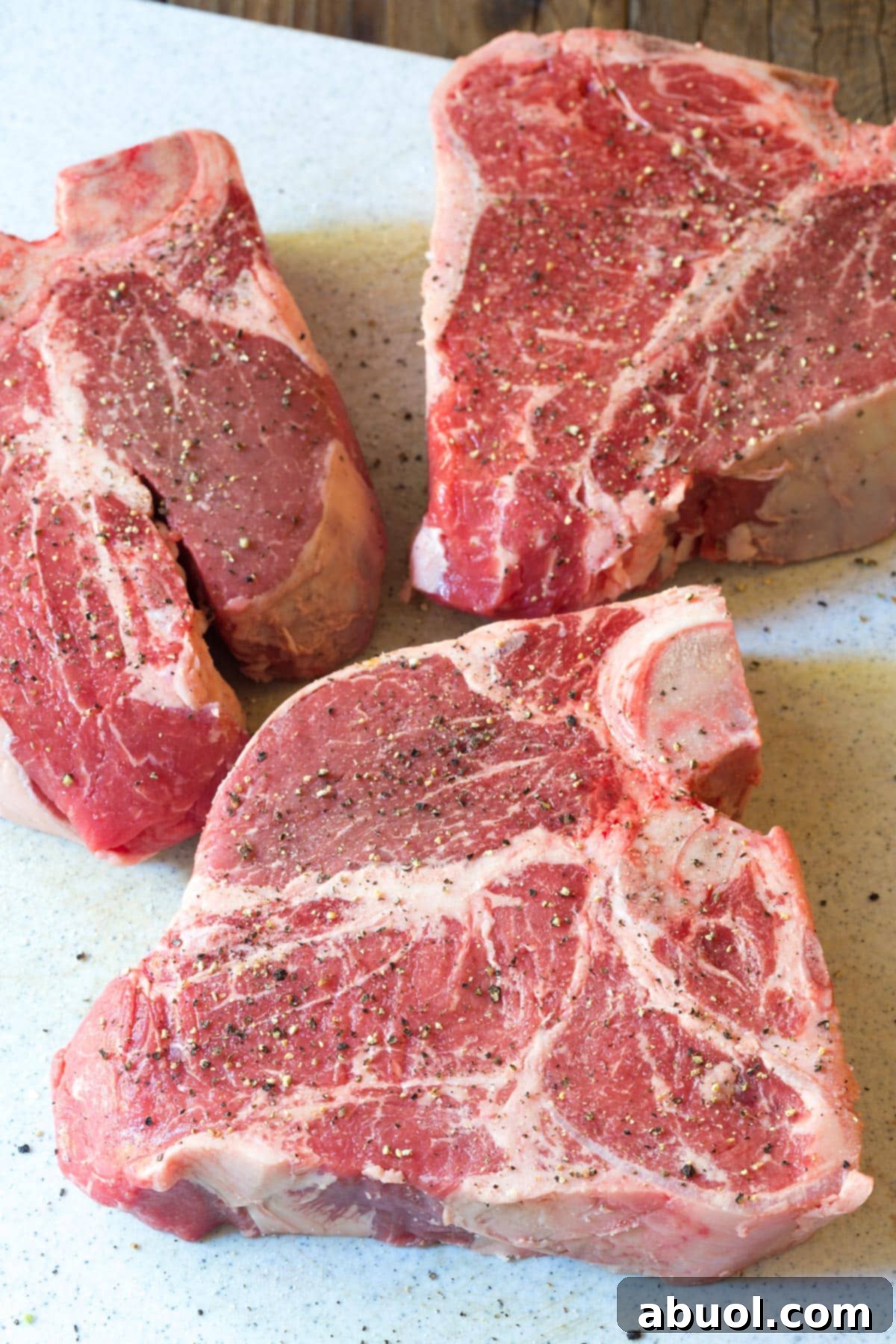 Steaks for Bistecca alla Fiorentina Recipe with salt and pepper on cutting board