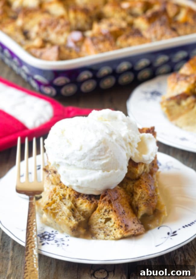 Piece of bread pudding topped with a scoop of ice cream on a white plate.