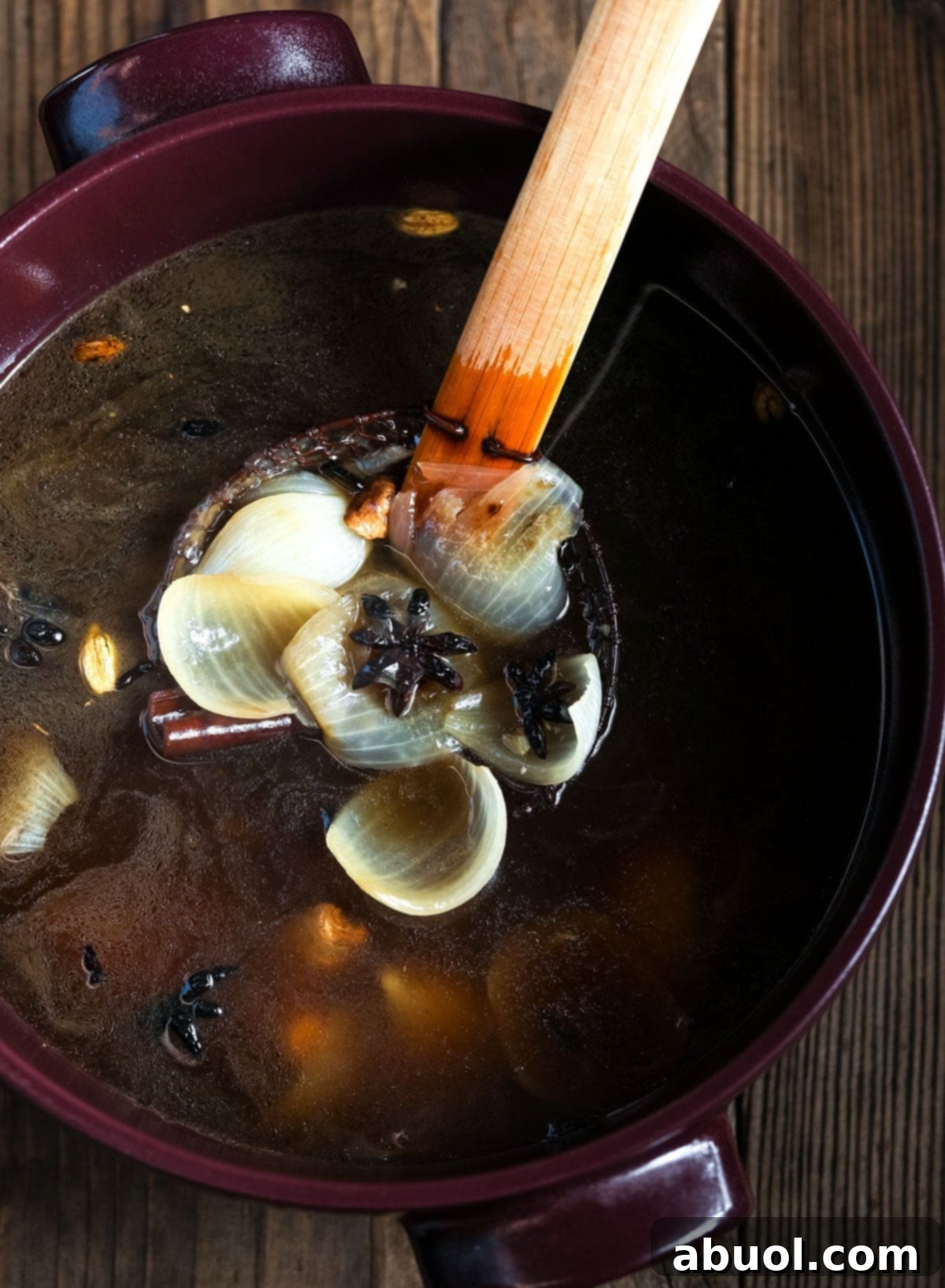 A close-up of a large pot filled with fragrant pho broth, with a ladle resting inside, ready to be served.