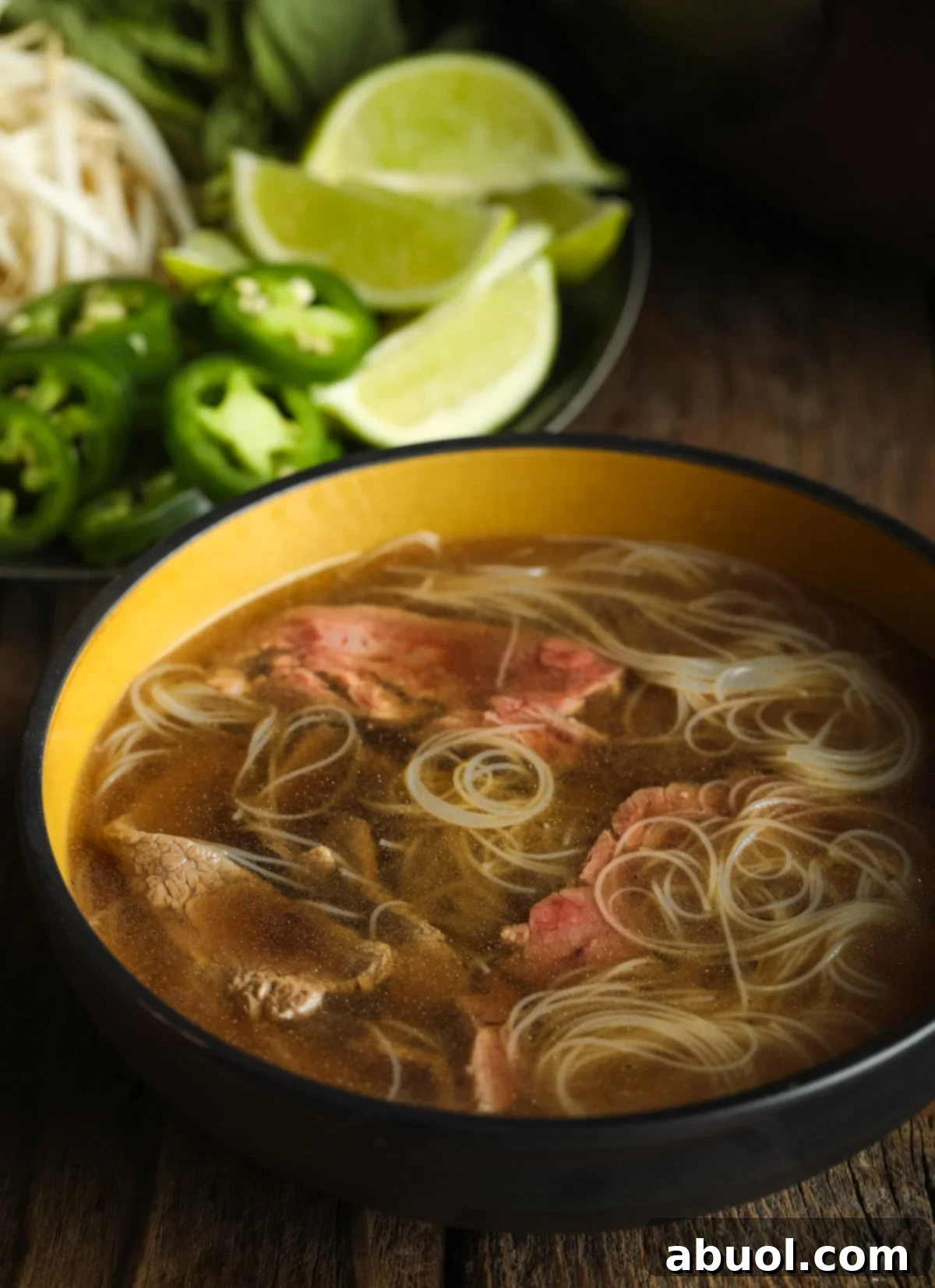 A large bowl of paleo pho soup, featuring a rich broth, tender slices of beef, and a generous array of fresh garnishes, presented beautifully for a healthy meal.