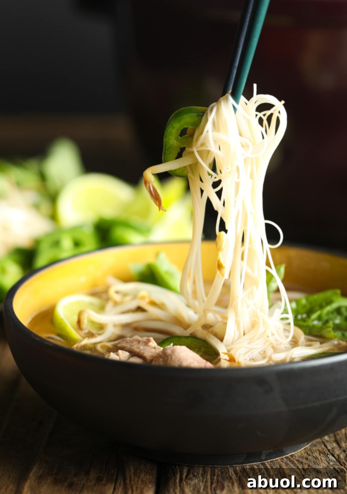 Chopsticks lifting a generous portion of translucent miracle noodles from a bowl of pho, highlighting their texture and how well they blend with the soup.
