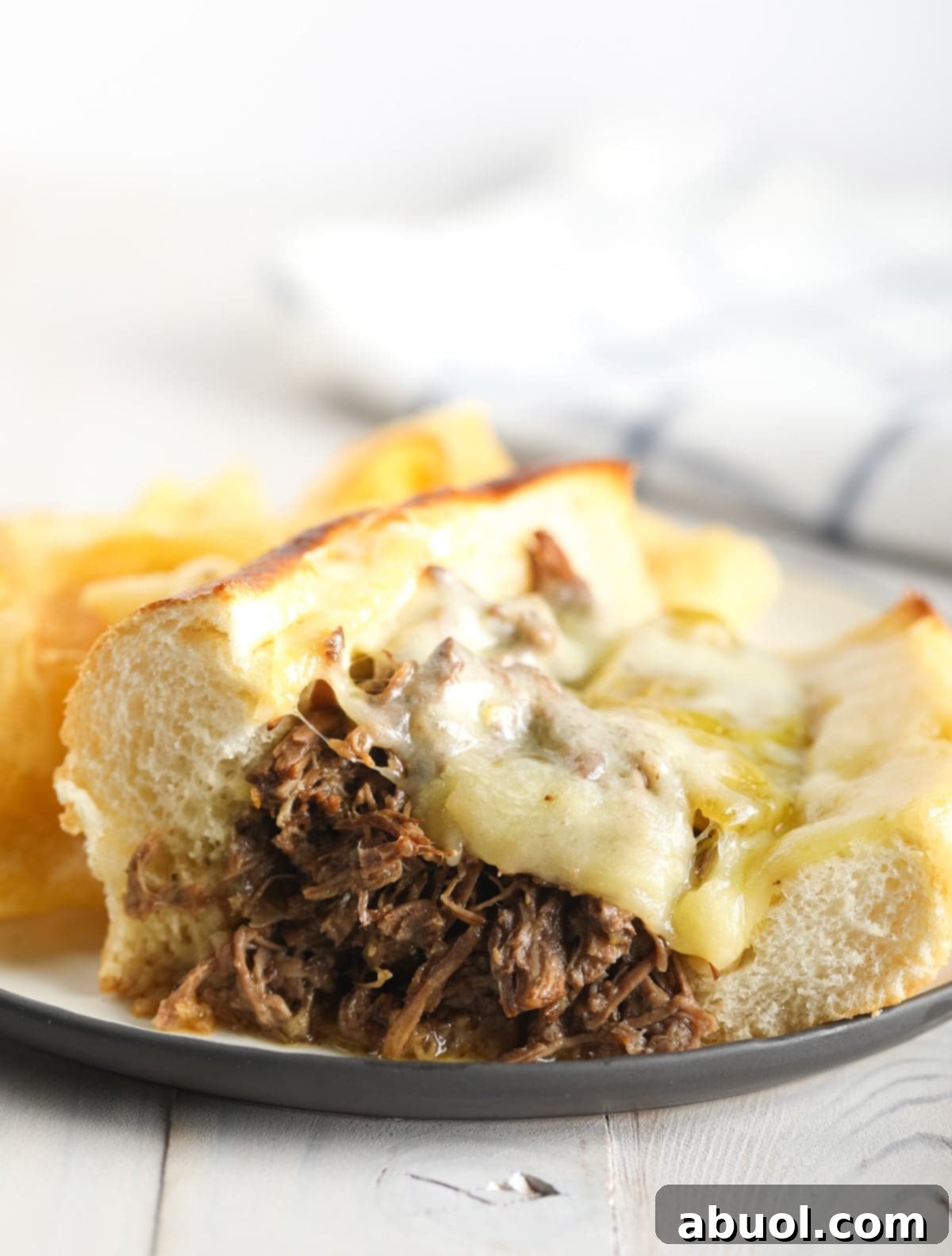 Italian beef sandwich with melted cheese on top on a plate. 