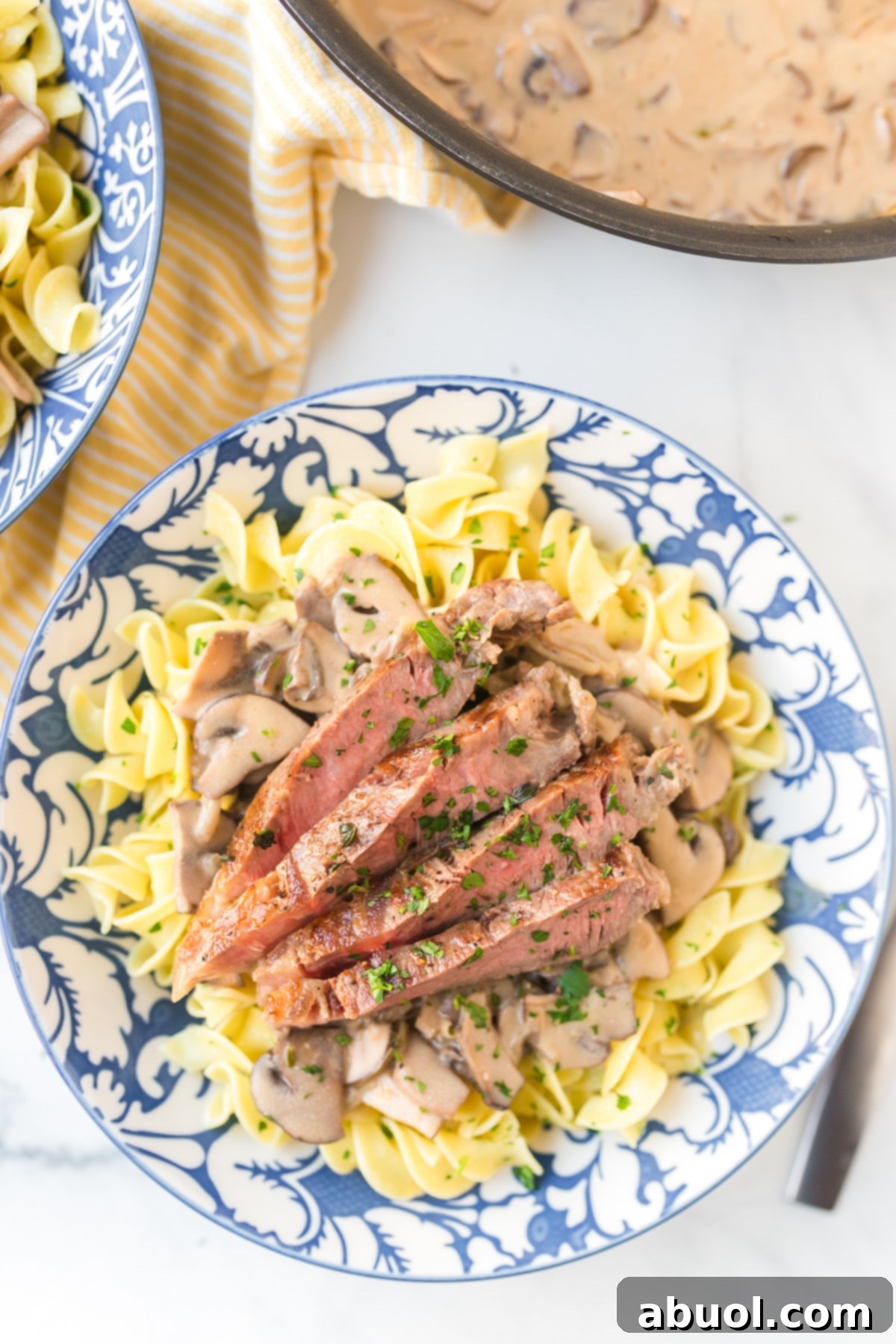 Quick Creamy Beef Stroganoff and Buttered Noodles 8 A close-up shot of Best Beef Stroganoff with Butter Noodles in a bowl, garnished with fresh parsley.