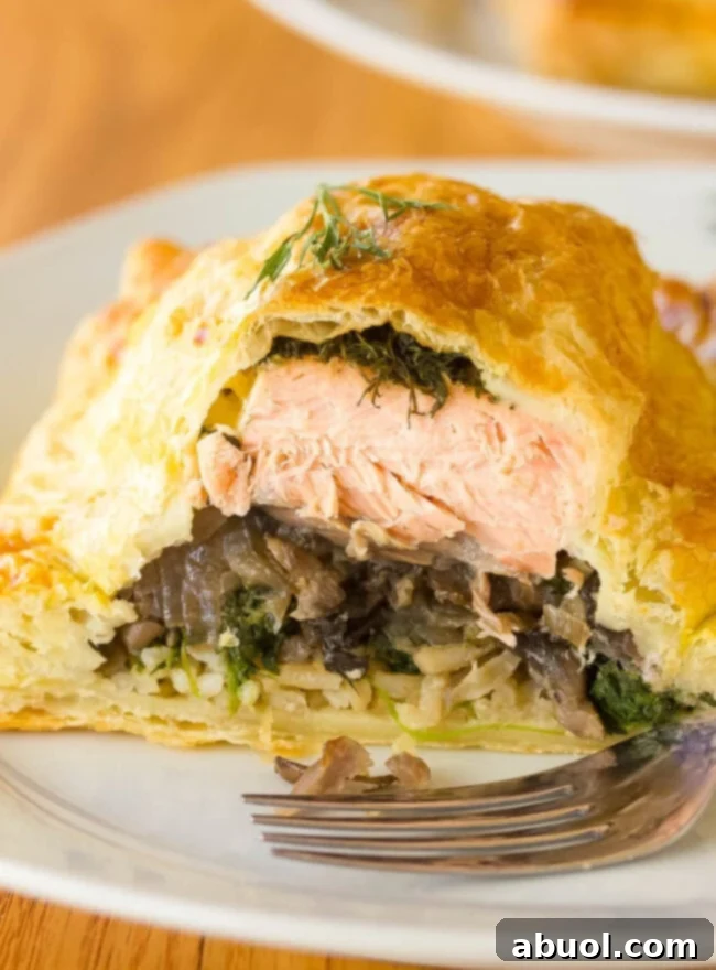 Gourmet Salmon En Croute 2 Salmon Coulibiac AKA Salmon Wellington cut open to show layers of salmon, rice, mushrooms, and spinach
