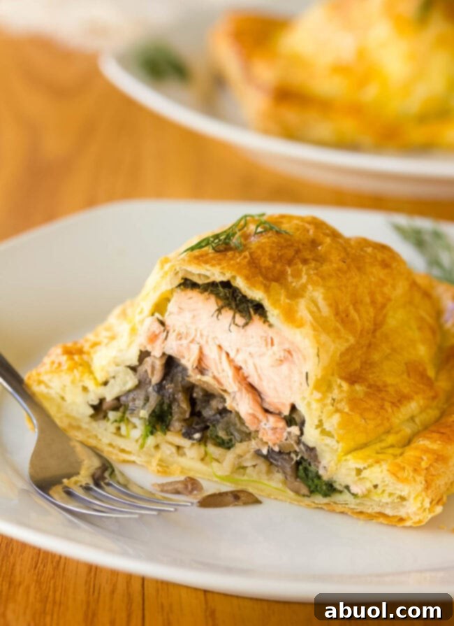 Gourmet Salmon En Croute 10 Holiday Salmon Wellington (salmon en croute) cut open to expose the layers of salmon, rice, mushrooms, and spinach