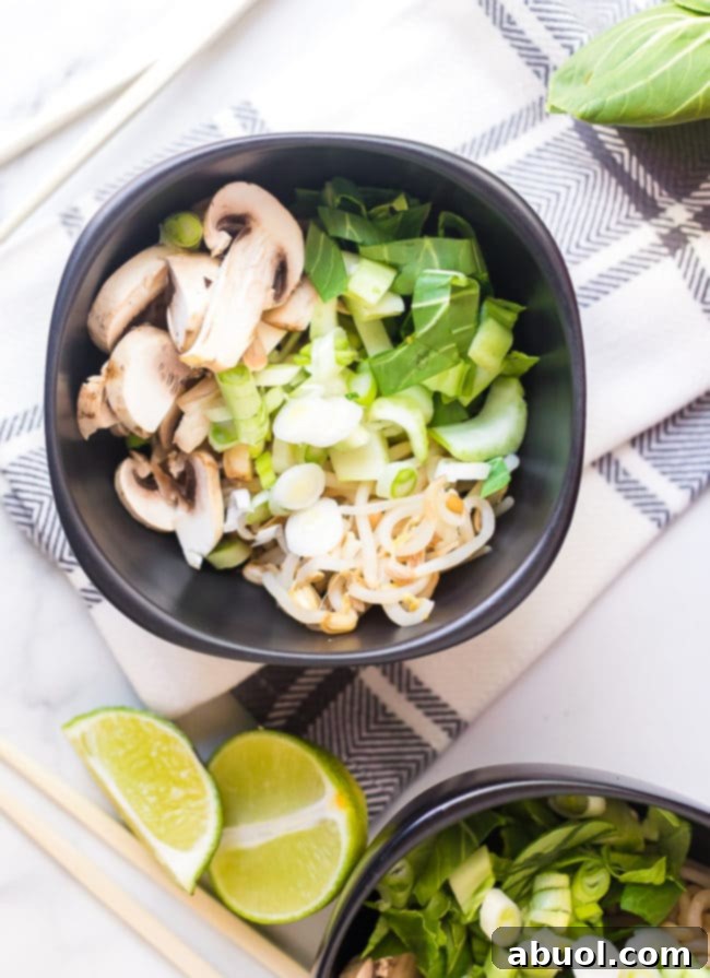 A vibrant collection of fresh hot pot ingredients, including sliced chicken, various vegetables, and noodles, neatly arranged in a bowl before cooking.