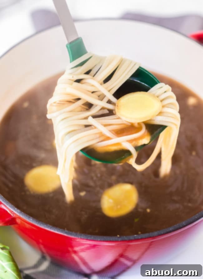 A ladle carefully lifting a generous serving of hot, steaming broth and delicate noodles from the pot, showcasing the inviting texture of the hot pot.