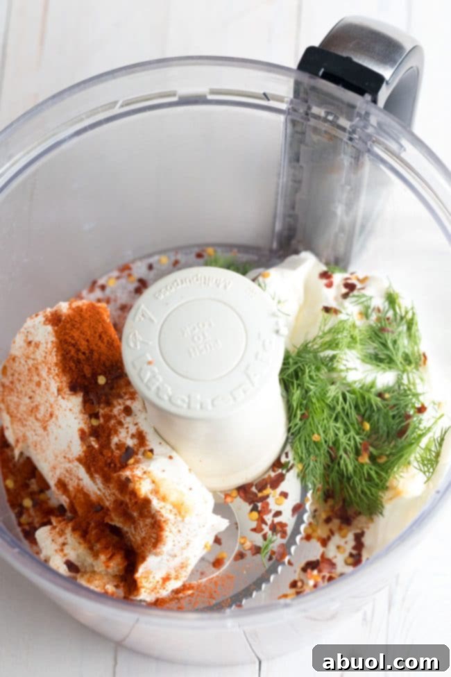 Creamy Smoked Salmon Dip 4 Half of the dip ingredients, including cream cheese, sour cream, and spices, placed in a food processor ready to be blended.