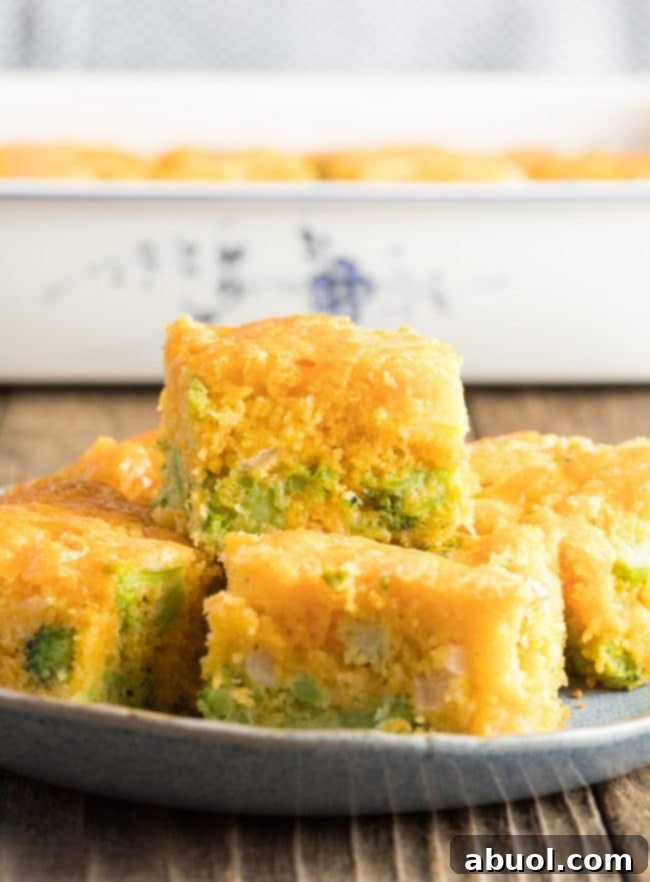 Stacked slices of fluffy broccoli cornbread on a plate, showcasing its tender texture and delicious additions of broccoli and melted cheese.