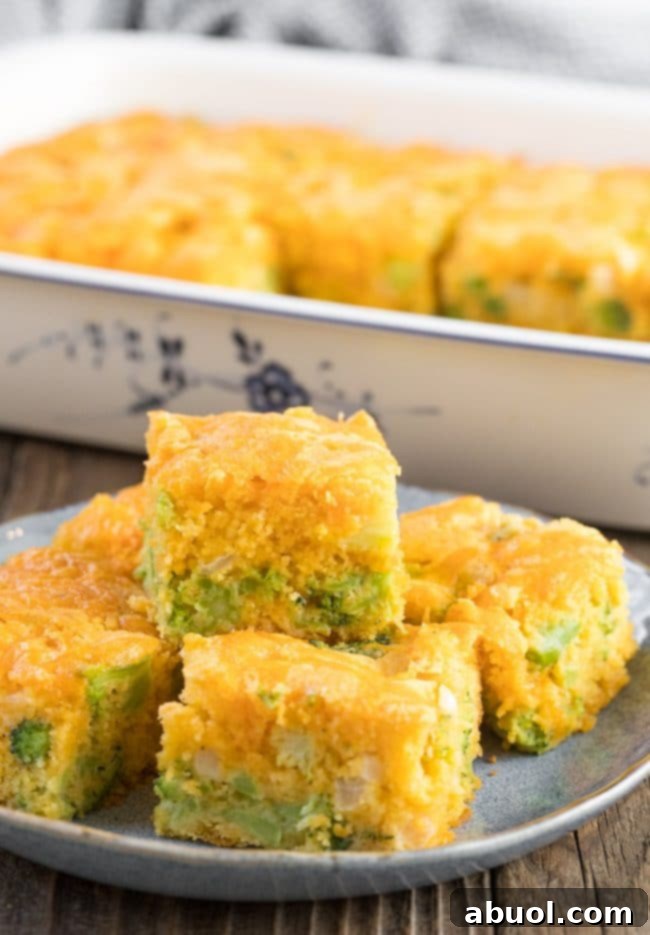 Broccoli cheese cornbread squares neatly stacked on a blue plate, highlighting their perfect golden crust and visible broccoli pieces, inviting a taste.