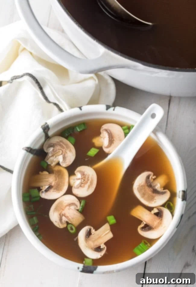Overhead shot of Japanese clear soup in a bowl with mushrooms and scallions.