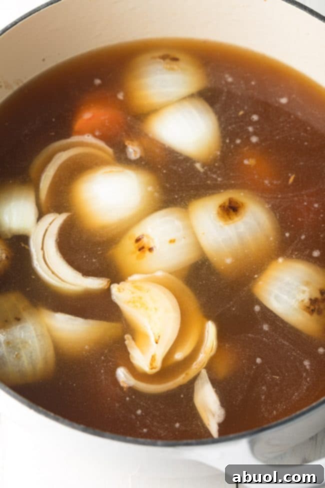 Soup simmering in a large pot with big pieces of veggies in it.