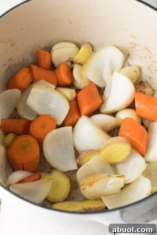 Carrots, onions, garlic and ginger being sautéed in a large stock pot.