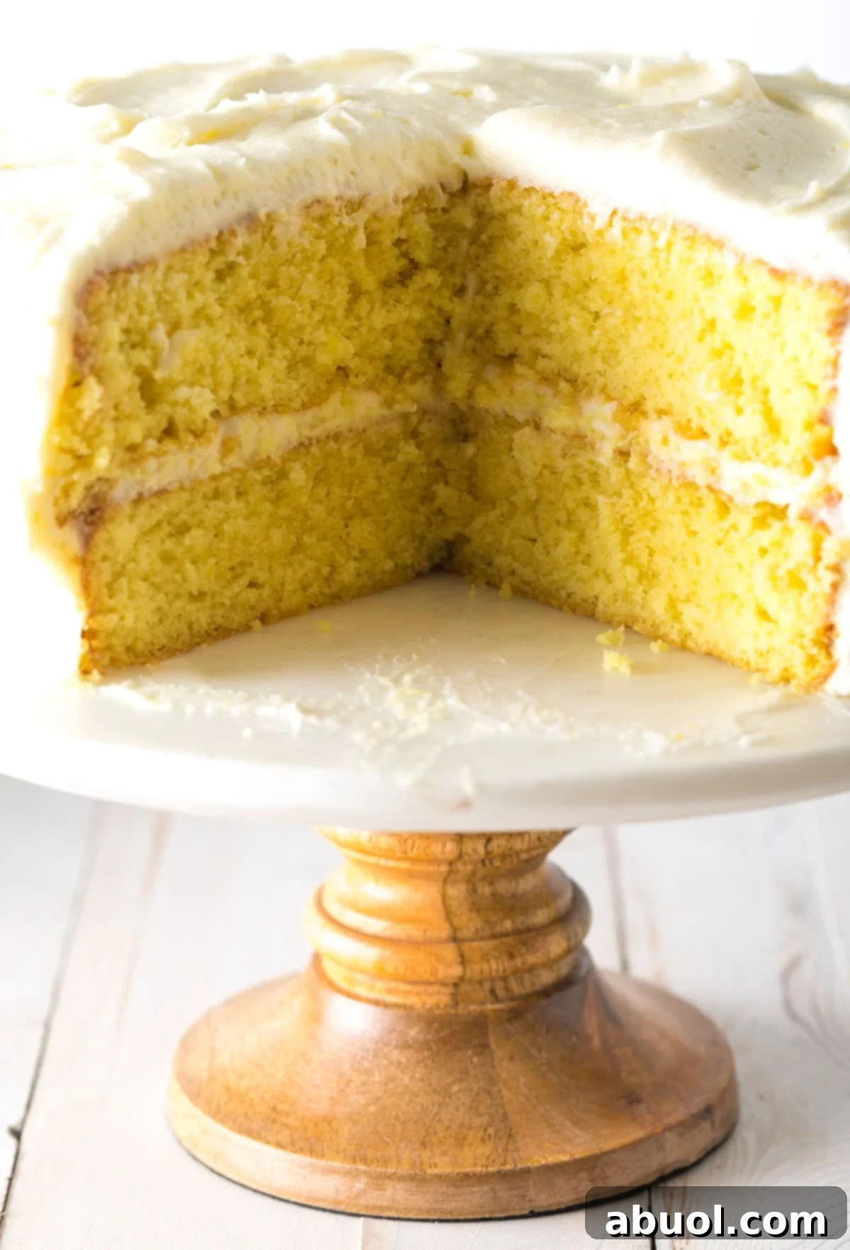 Lemon Cake on a cake stand with a slice taken out of the cake.