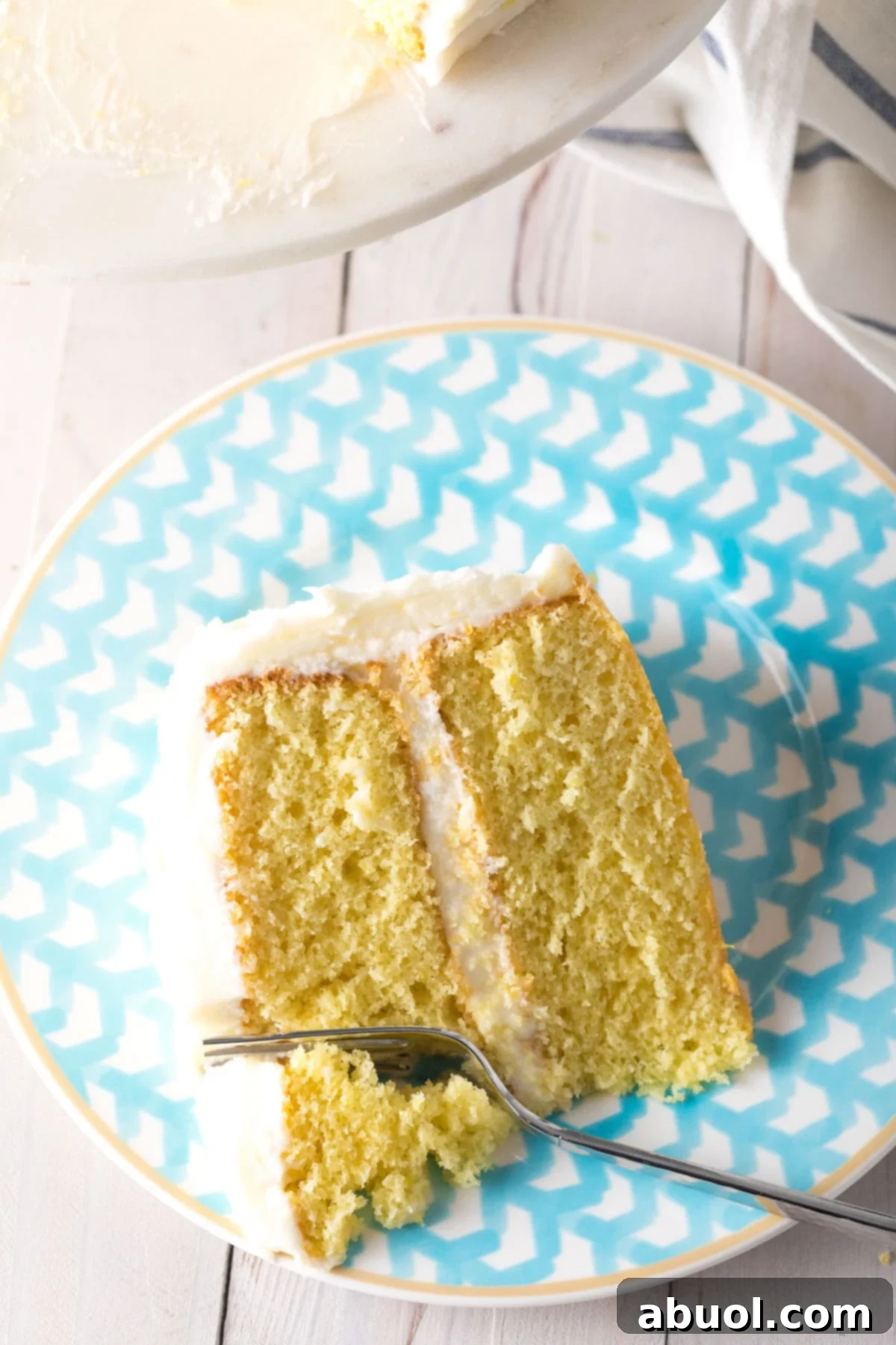 A top down view of a slice of lemon buttermilk cake with a fork taking a bite of it.