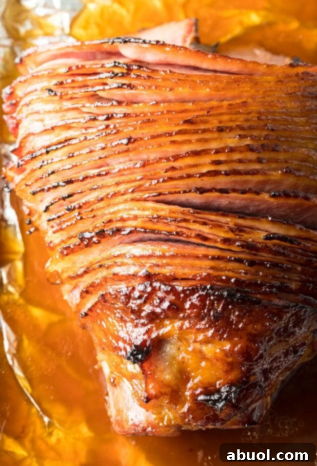 Close-up overhead shot of a baked ham with a glistening Coca-Cola glaze, still in the foil-lined roasting pan.