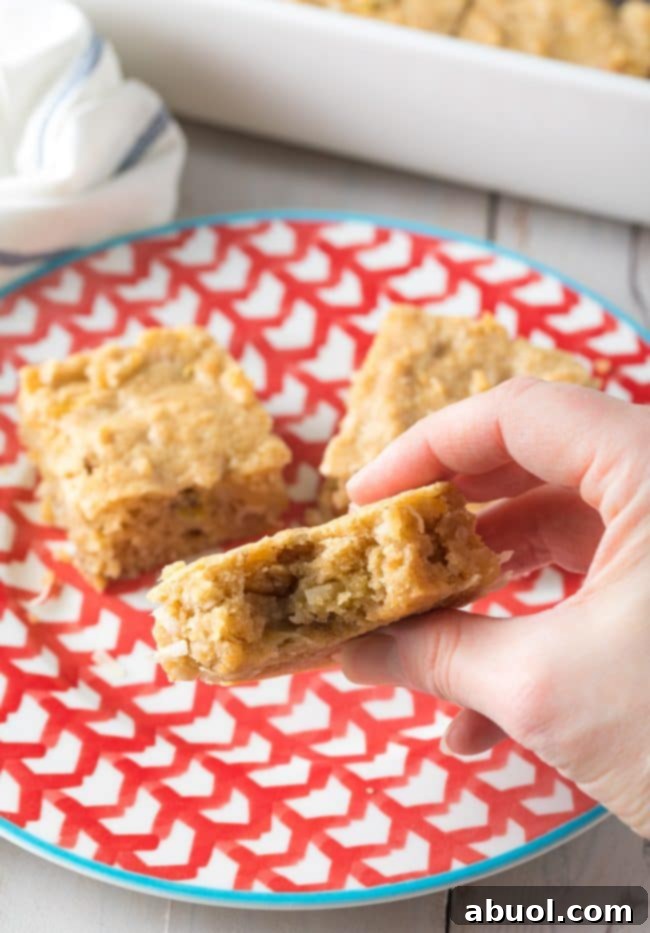 Pina Colada Blondies 9 Hand holding a blondie with a bite missing from it.