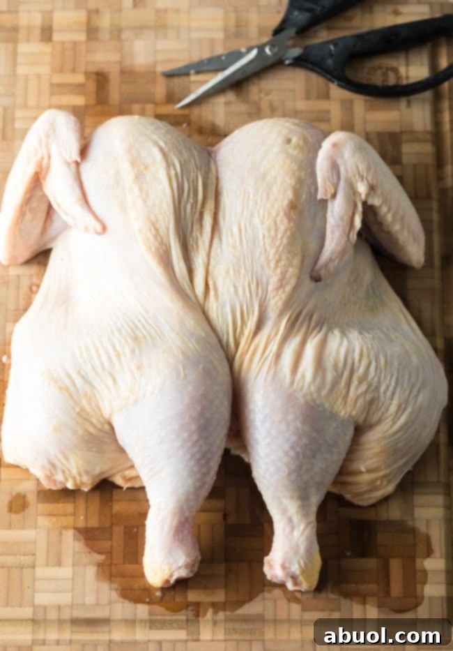 Finished spatchcocked chicken laid flat on a cutting board.