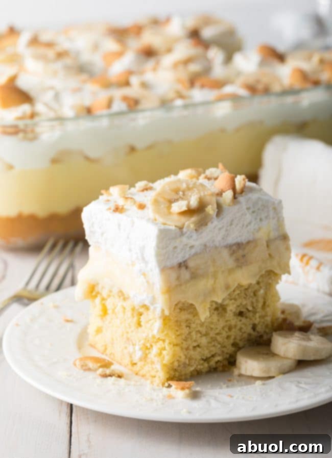 Decadent Banana Pudding Cake 9 Square slice of banana pudding cake on a white plate.