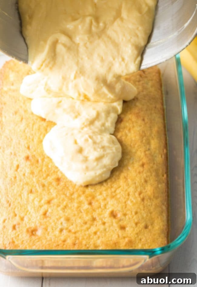 Decadent Banana Pudding Cake 6 Creamy pudding layer going on top of the cake layer in a baking dish.