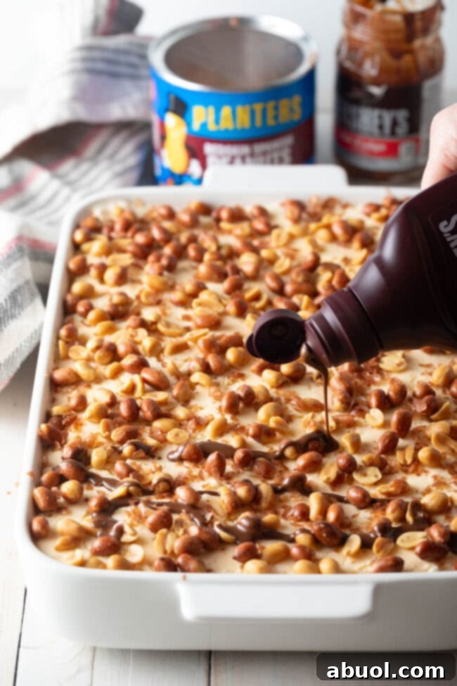 The final delicious touches: drizzling Magic Shell chocolate coating over the last layer of peanuts to secure them in place.