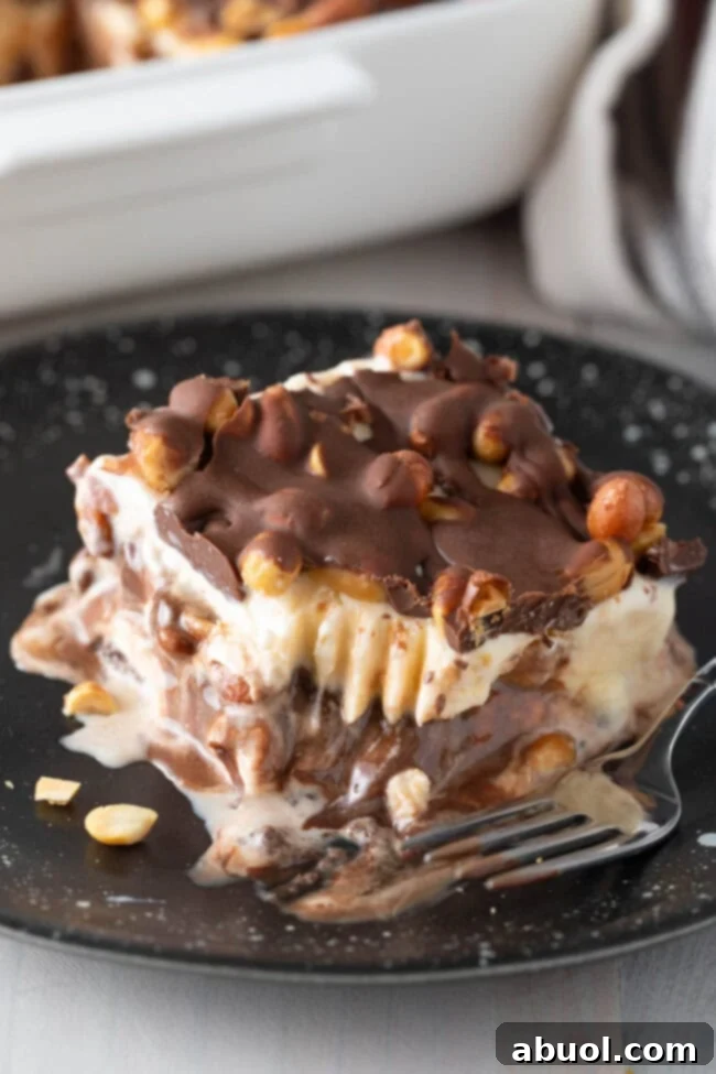 A tantalizing Buster Bar Ice Cream Cake copycat on a plate with a delicious bite already taken, showcasing its irresistible layers. 