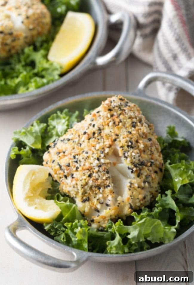 Flaky baked cod with a golden everything bagel crust, served on a bed of fresh lettuce with a bright lemon wedge.