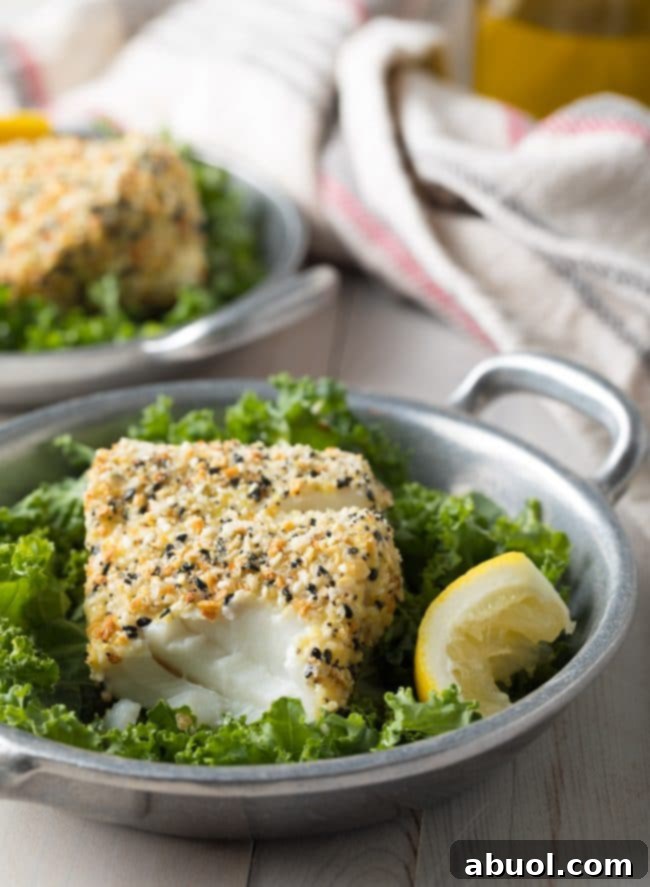 Close-up of baked cod with everything bagel seasoning, showing a fork flaking off a tender piece of fish.