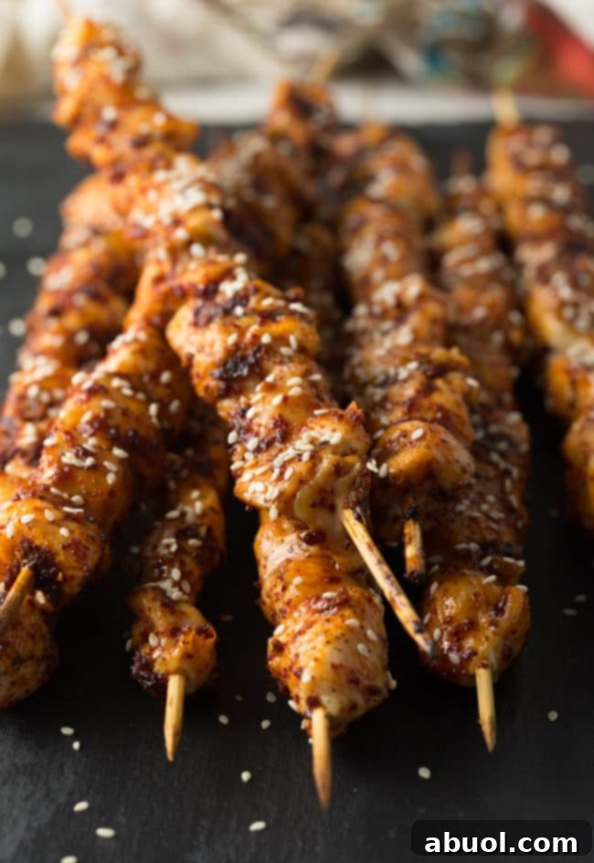 Two finished Korean chicken skewers on a serving plate with fresh garnishes.