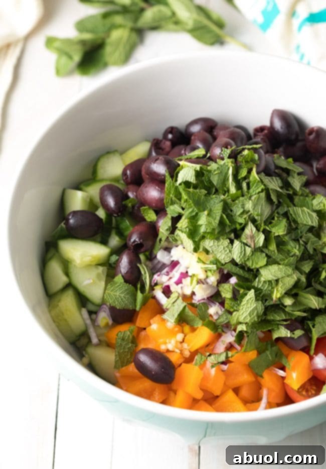 Easy Greek Horiatiki (Village Salad) Recipe - The vibrant herb vinaigrette being poured over the colorful chopped vegetables.