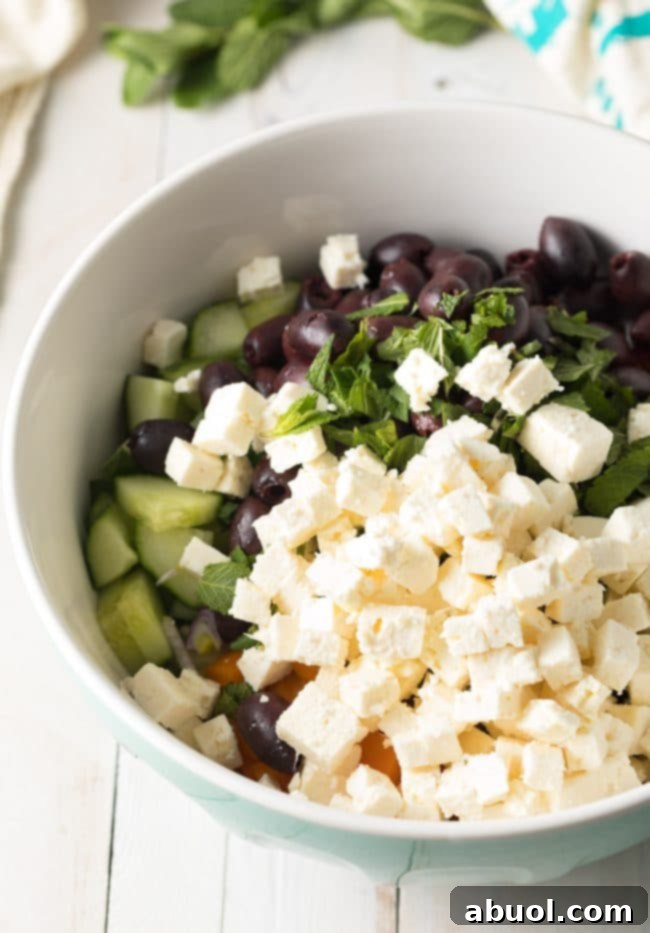 Mixing the Horiatiki Greek Village Salad with the dressing, ensuring all chunks are coated.
