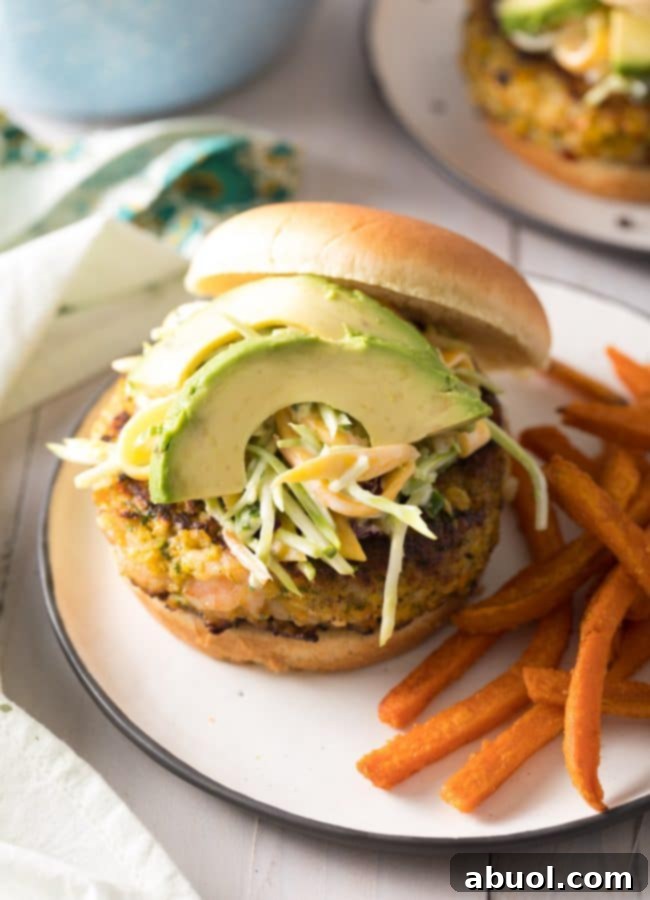 Gourmet Shrimp Burgers 2 Zesty Caribbean Shrimp Burgers on a plate with fresh avocado slices and vibrant mango slaw, ready to be enjoyed.