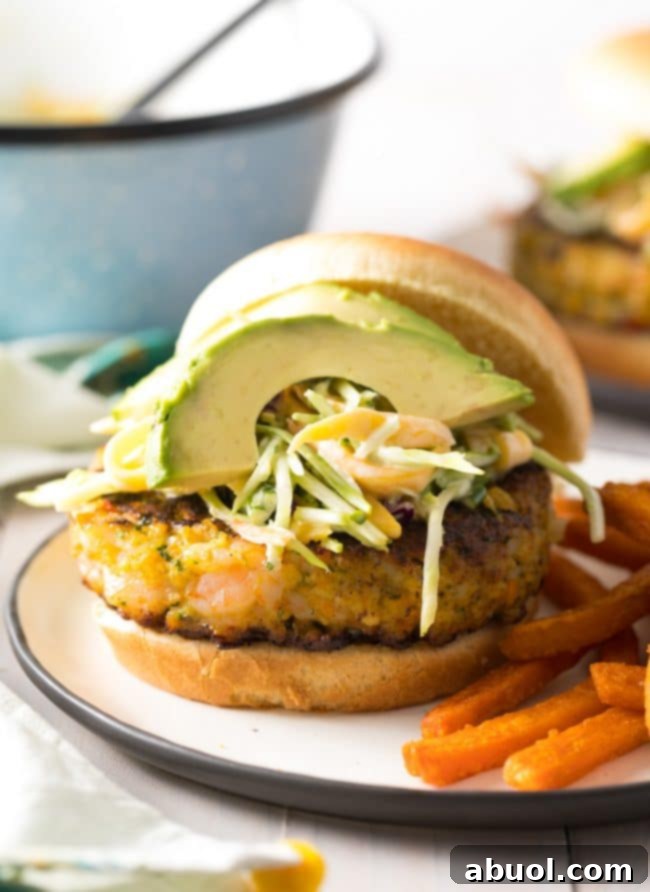 Gourmet Shrimp Burgers 14 A mouthwatering Caribbean Shrimp Burger overflowing with fresh toppings including mango slaw and avocado slices, highlighting its gourmet appeal.