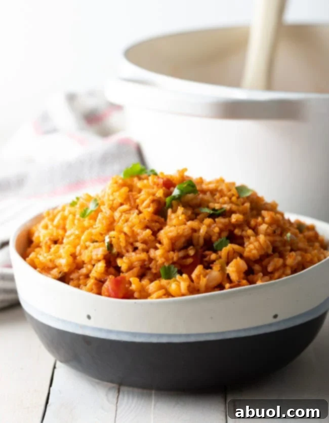 A serving bowl filled with steaming, perfectly cooked Mexican rice, garnished with fresh cilantro.