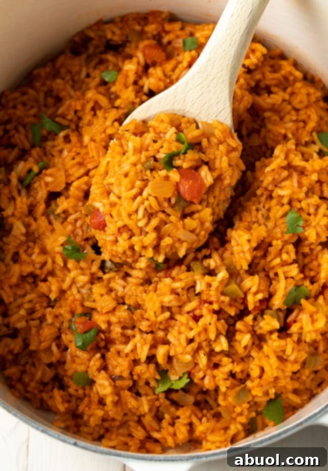 A close-up shot of perfectly cooked, fluffy Mexican rice inside a pot, with a wooden spoon ready to serve.