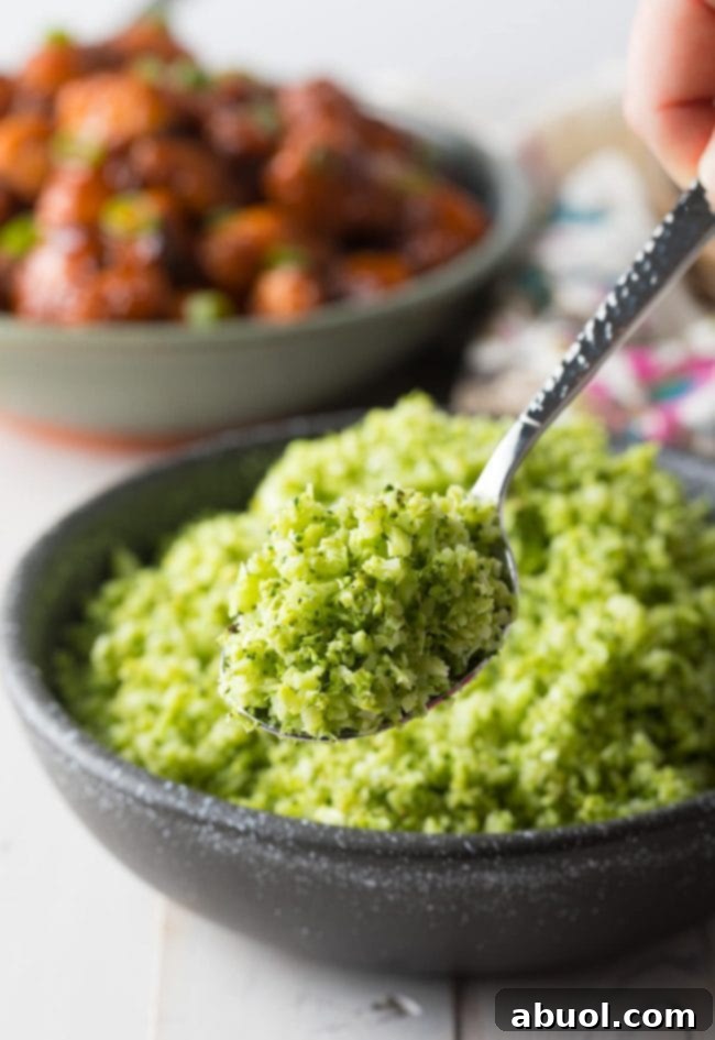 A metal spoon scooping up a portion of the roasted broccoli rice, highlighting its tender yet textured consistency.