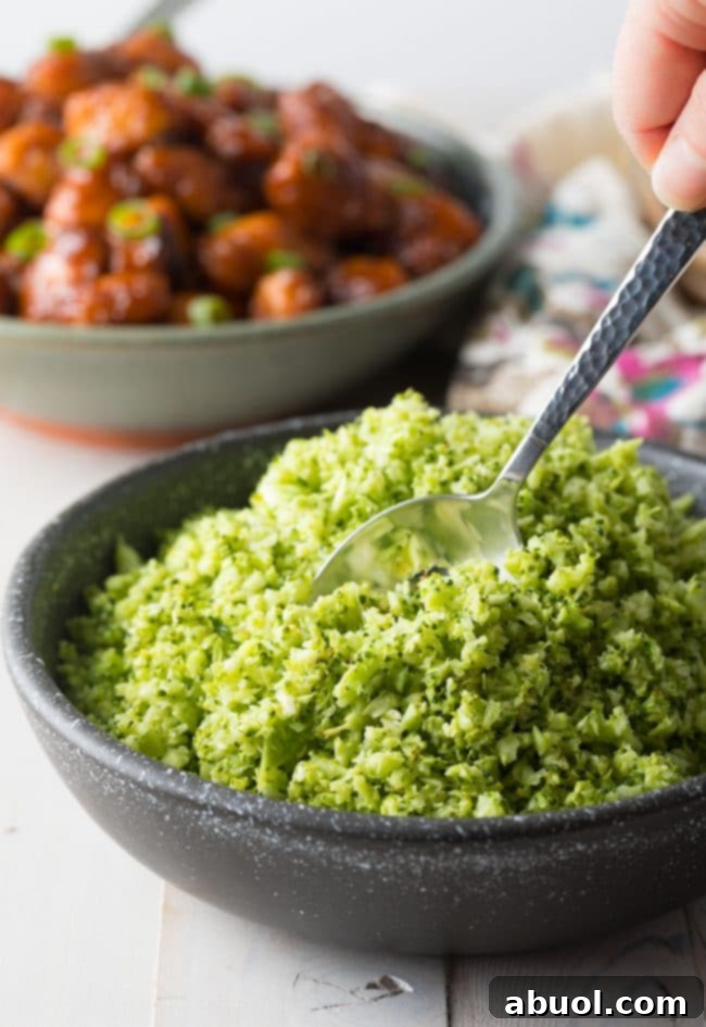 A close-up side view of a serving of roasted broccoli rice in a black dish, showing its appealing texture and readiness to be enjoyed.