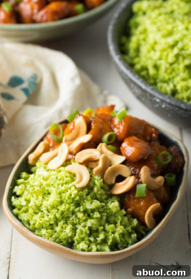 A vibrant dish of orange chicken with cashews, perfectly complemented by a serving of healthy broccoli rice, showcasing a delicious meal combination.