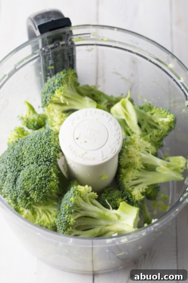 The second step in preparing broccoli rice, focusing on processing the broccoli florets, demonstrating the 'then tops' technique for optimal texture.