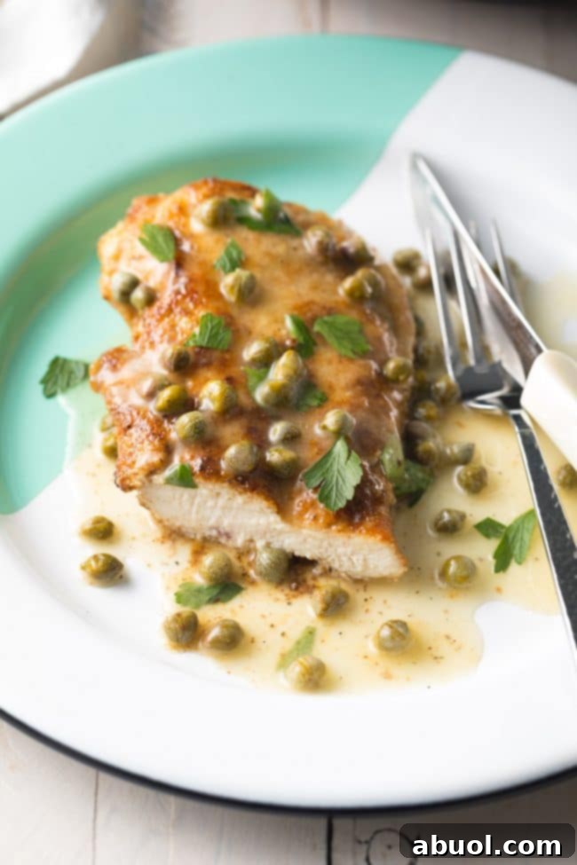 A serving of crispy chicken piccata with lemon caper sauce on a white plate, ready to be enjoyed.