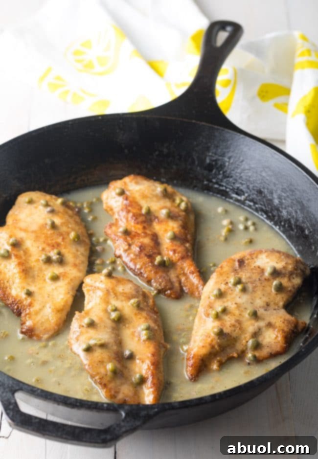 Chicken piccata being garnished with fresh parsley.